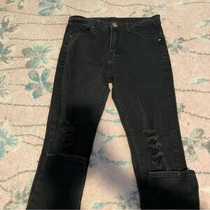 Black distressed jeans with rips on the knees and a button fly